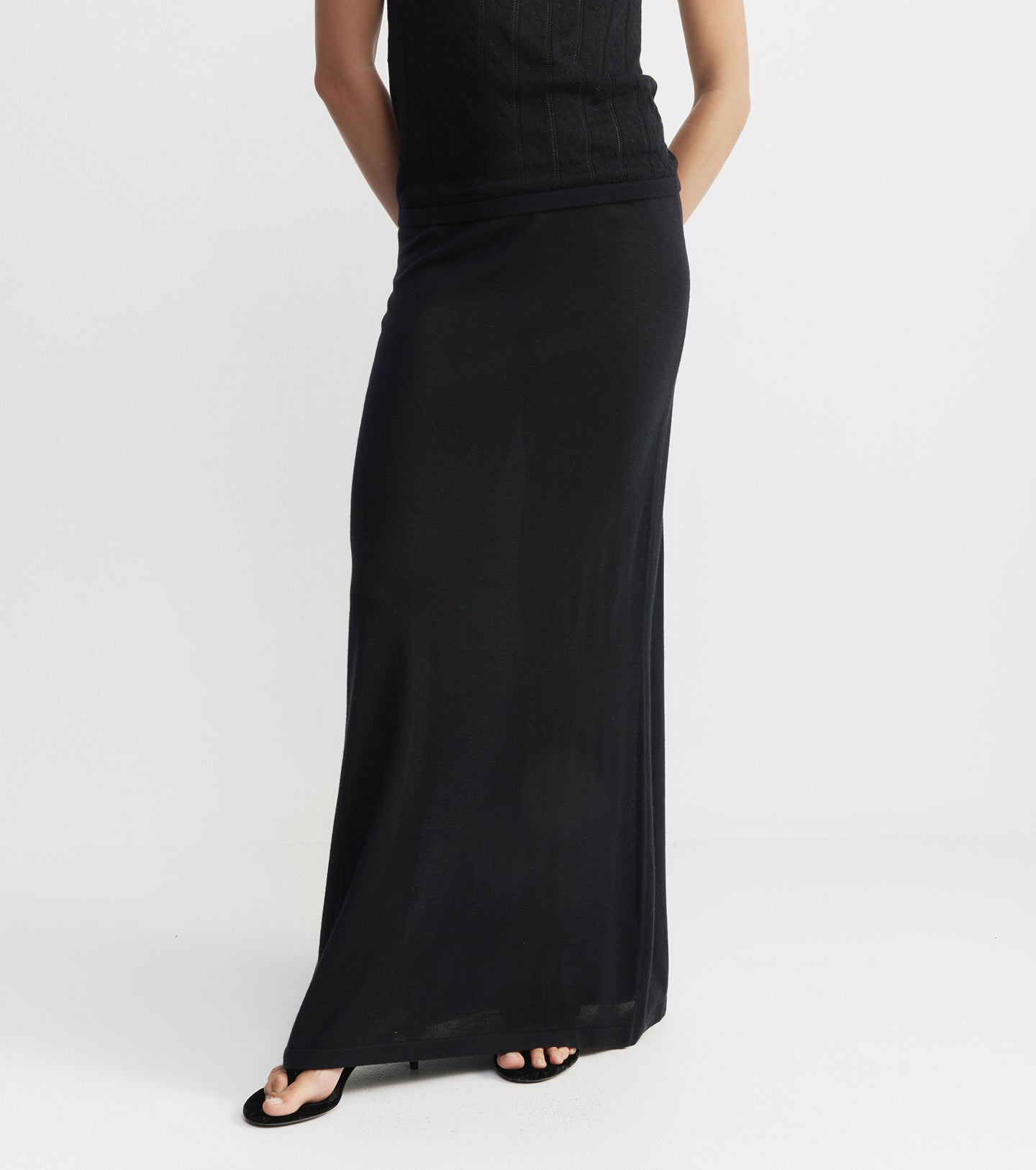Black long dress worn by a person on a white background