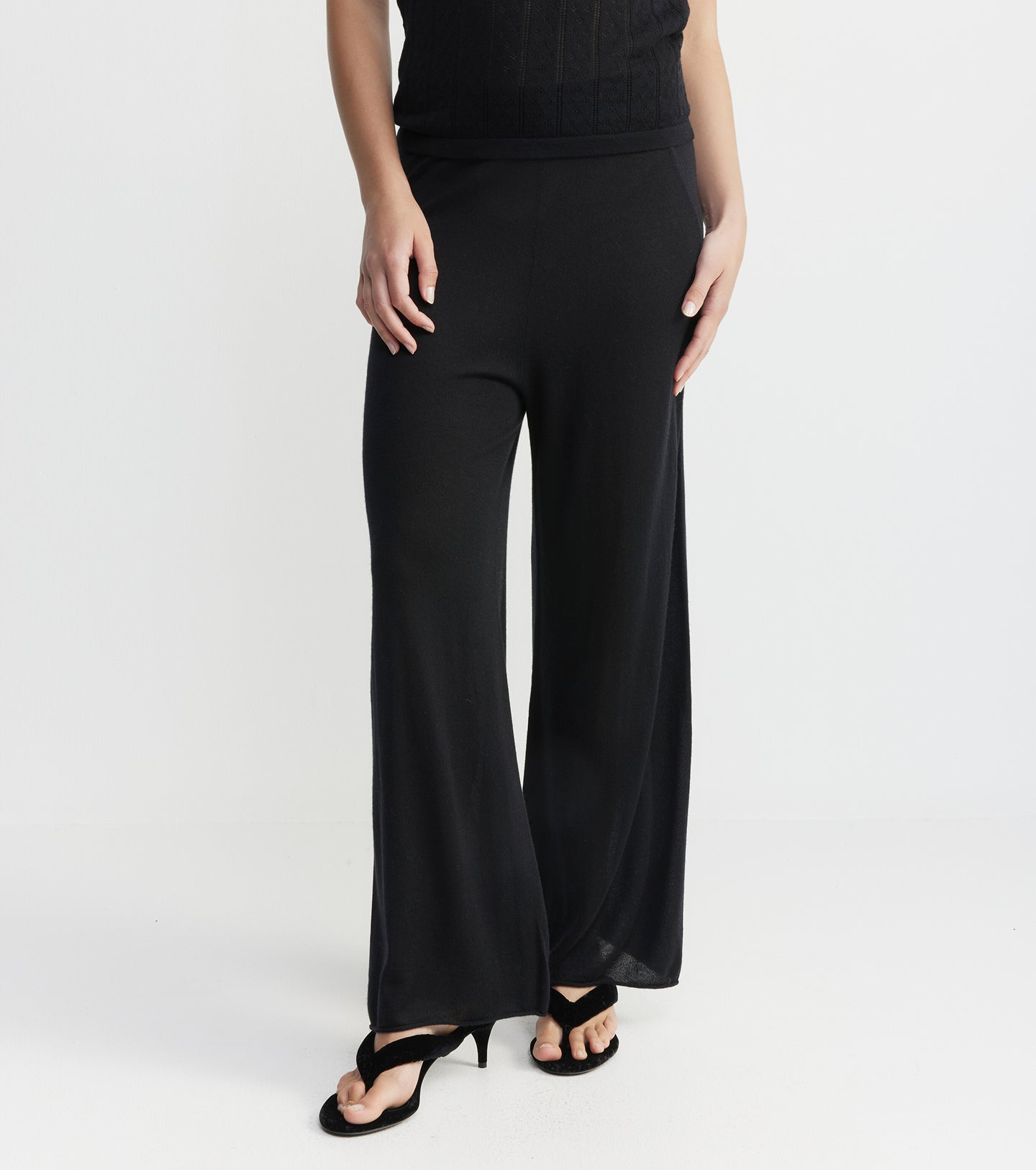 Black wide-leg pants worn by a person on a white background