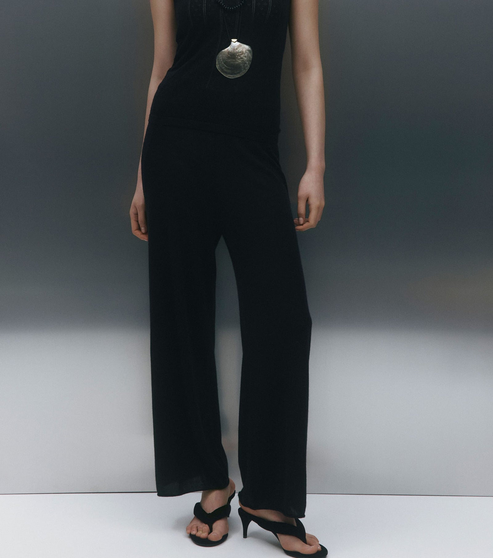 Person wearing a black jumpsuit with a plain background